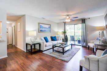A living room with a white couch and a painting on the wall.